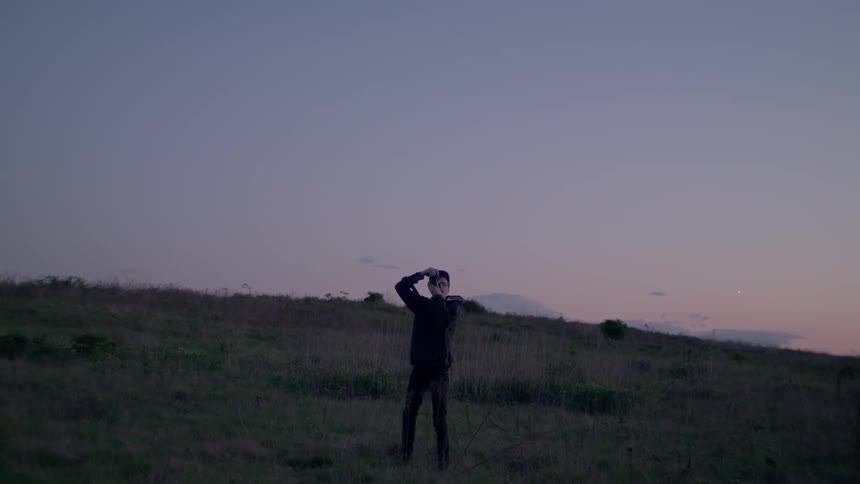 A man stands on the grass and focuses his camera for a photograph