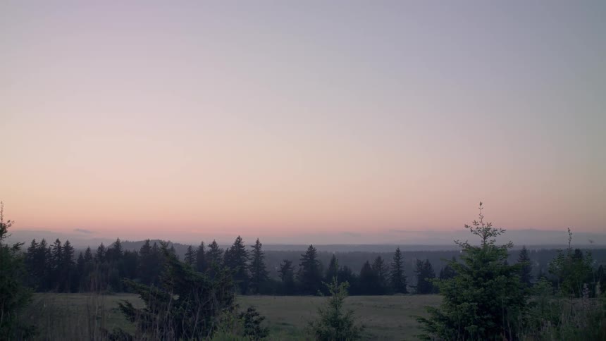 A sunset sky over trees and grass
