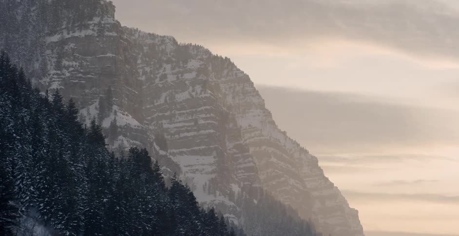 A mountain lined with snowy trees at sunset