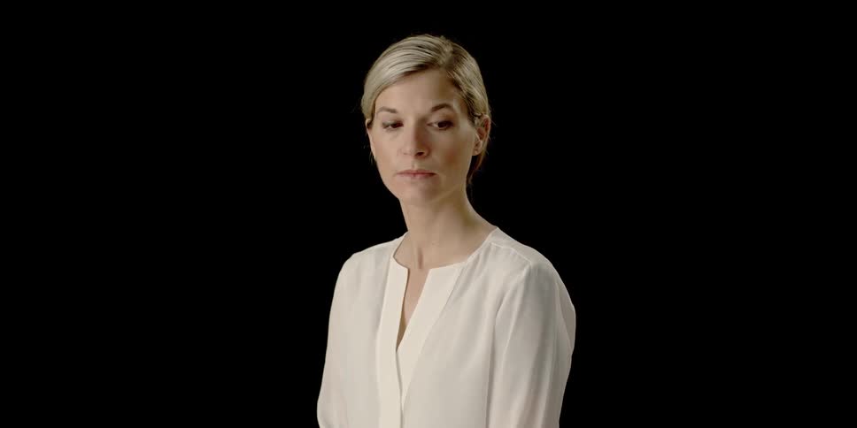 A professional woman looks down to the side then back up