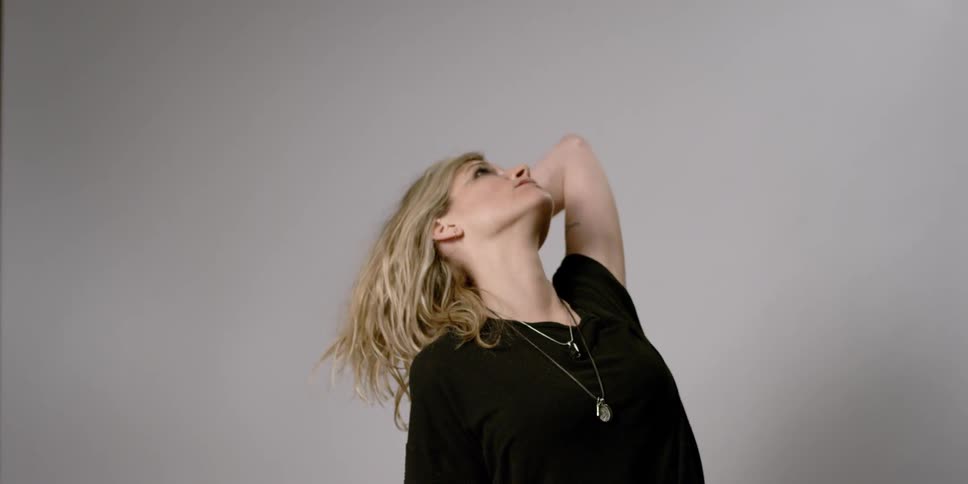 A woman leans her head back and runs her hand through her hair