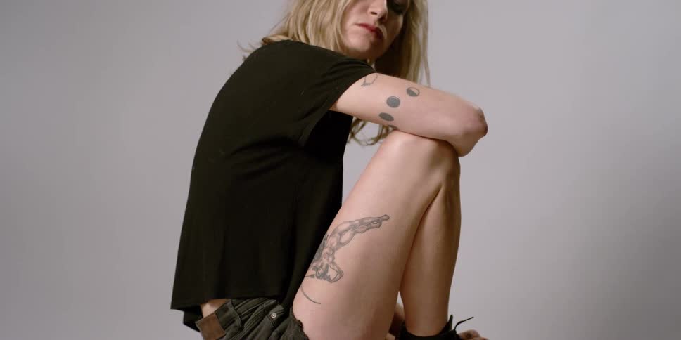 A woman sits down with her knees to her chest