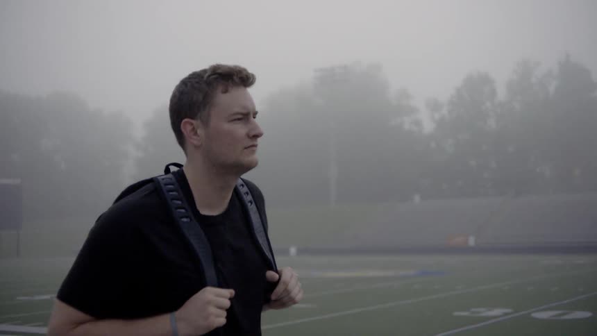A man walks down stadium bleachers while it rains