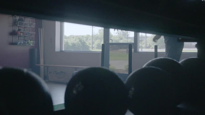 A man pushes weights back and forth across the floor