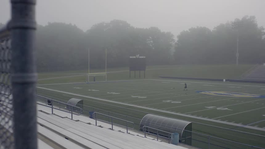 A person walks toward a ball on a football field