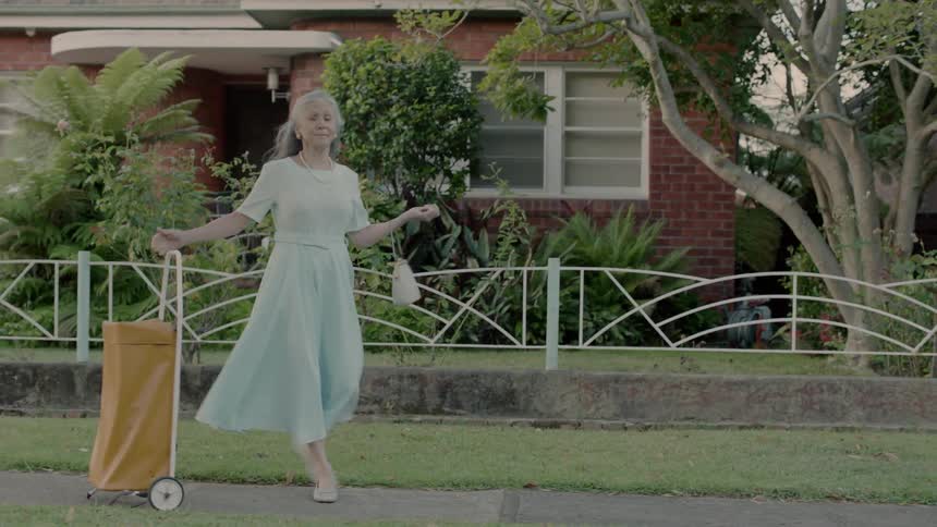 A woman is dancing as she walks down the sidewalk