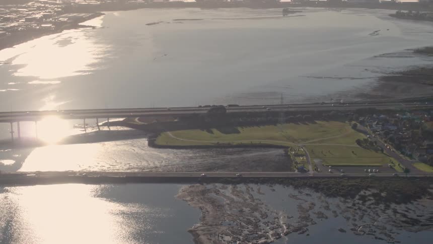 Cars cross a lake bridge on a sunny day