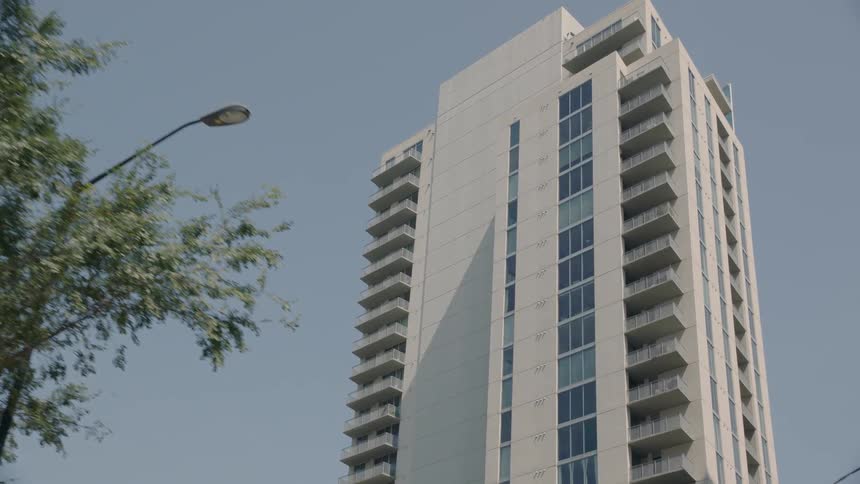 A high rise apartment tower stands out against a blue sky