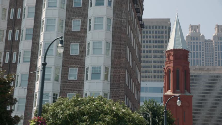 A hotel is being filmed by a passing car with a big city in the background
