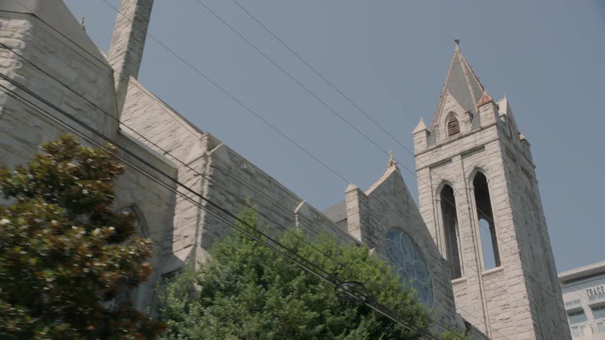 The steeple on an old church rises into a blue sky