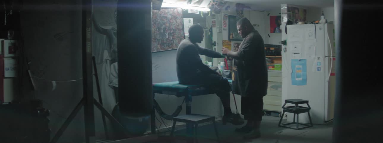 A coach is helping a boxer wrap his hand with tape
