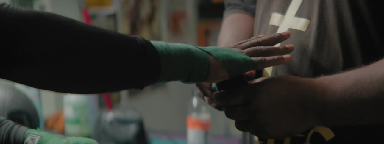 A man is getting his wrists taped up by his coach