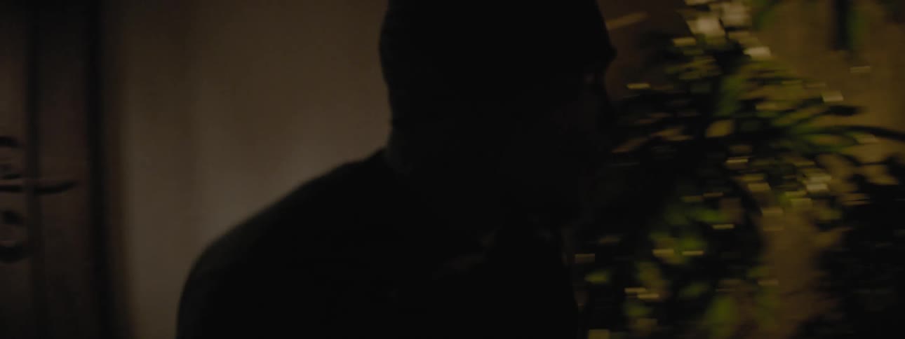 Man opens and closes a door and walks past a chain link fence