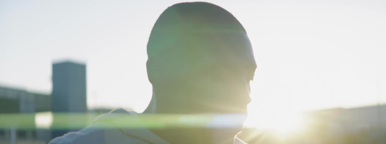 An athlete is taking deep breaths as he stands outside at dawn