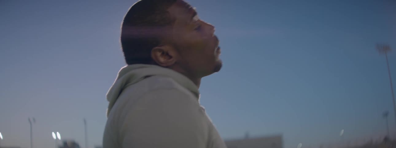 A man in sweats is walking with a large light above him