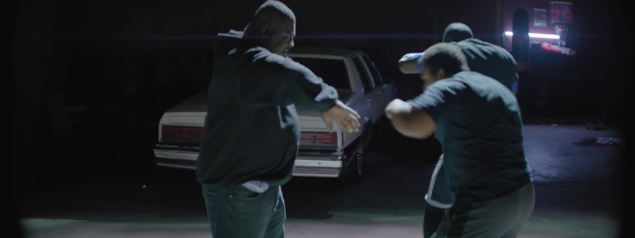 Two men practice boxing while a third man coaches them