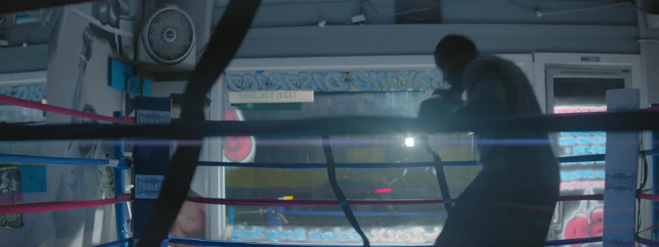 A boxer practices in a ring while city traffic moves outside
