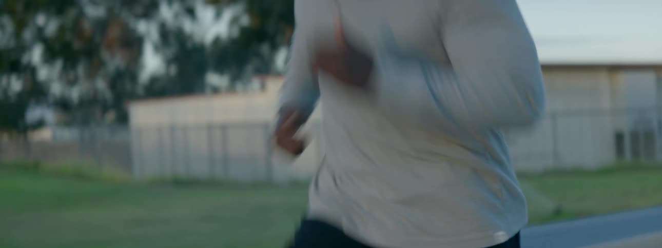 A man is jogging down the street on a cloudy day