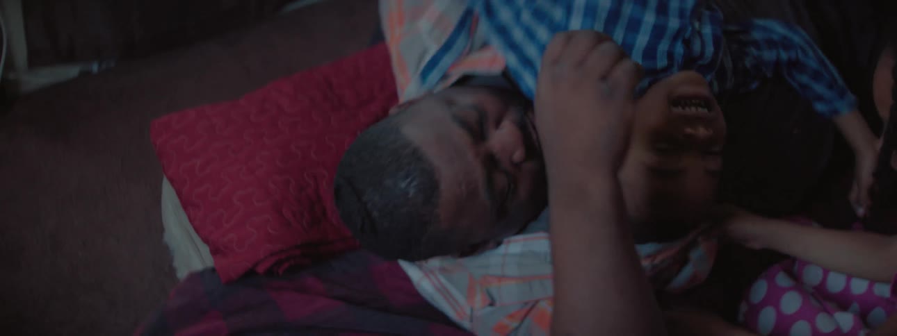 A man rough houses with kids on the floor