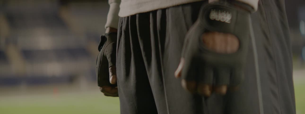 An athlete standing outside flexes his hands and clenches his fists