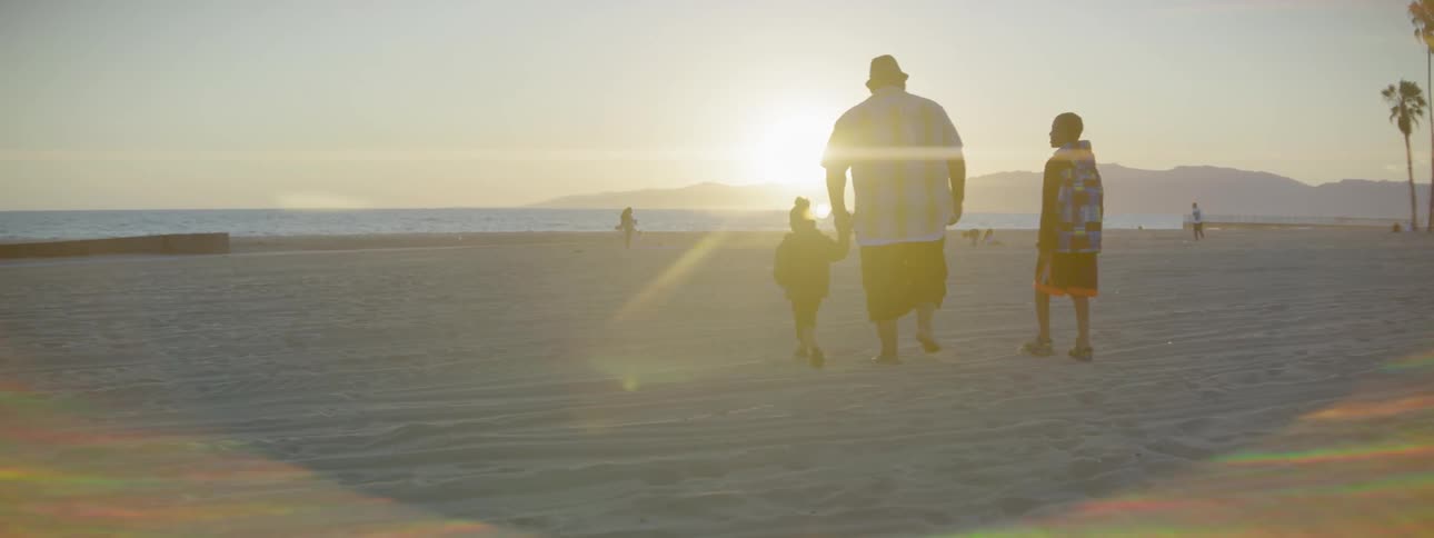 A man walks with children at the beach