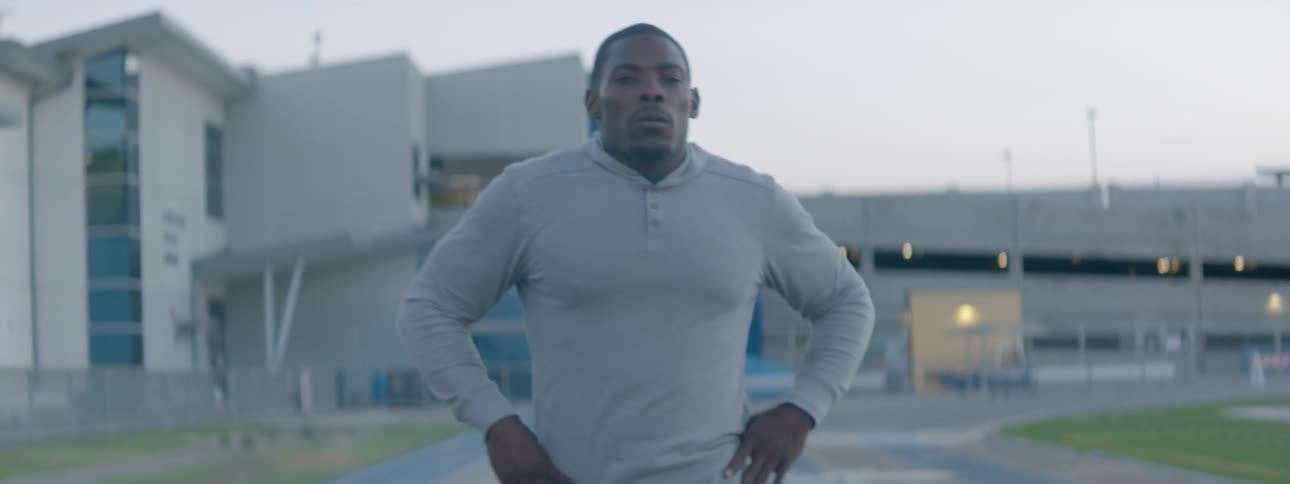 Man runs on a track and stops to catch his breath