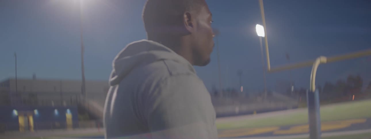 A man in sweats is walking a football field