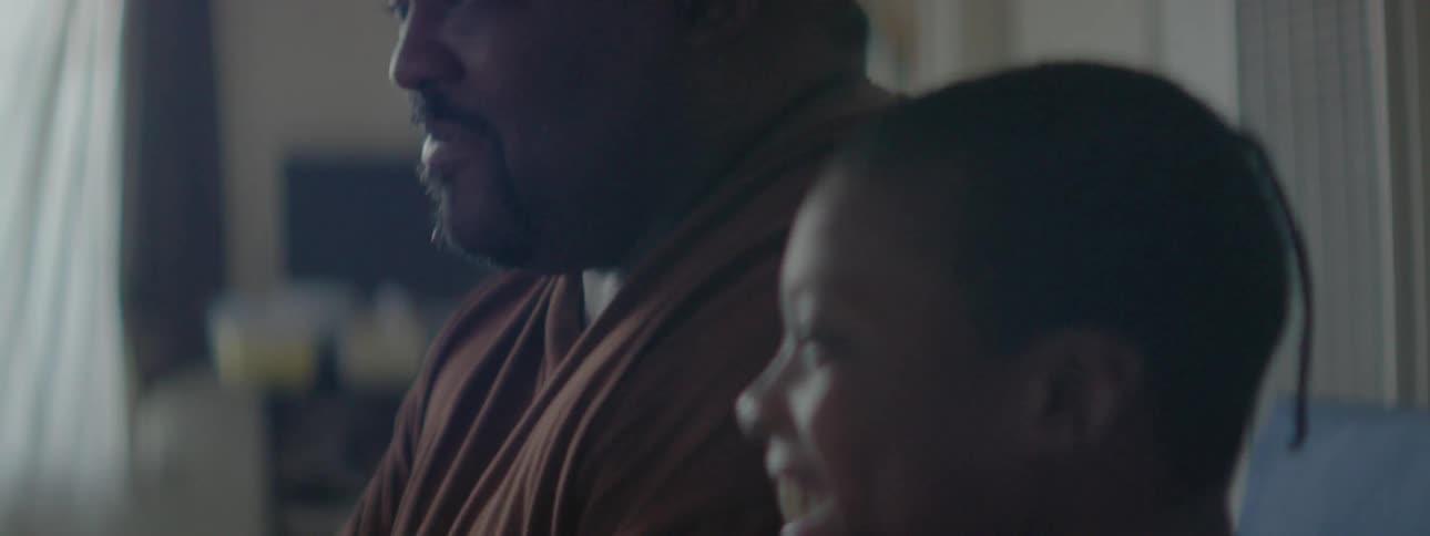 A large man is sitting and watching something with his son