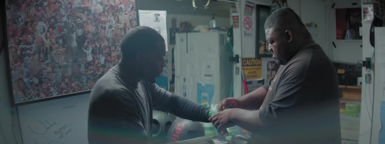 Man wraps another man's wrist with a green bandage