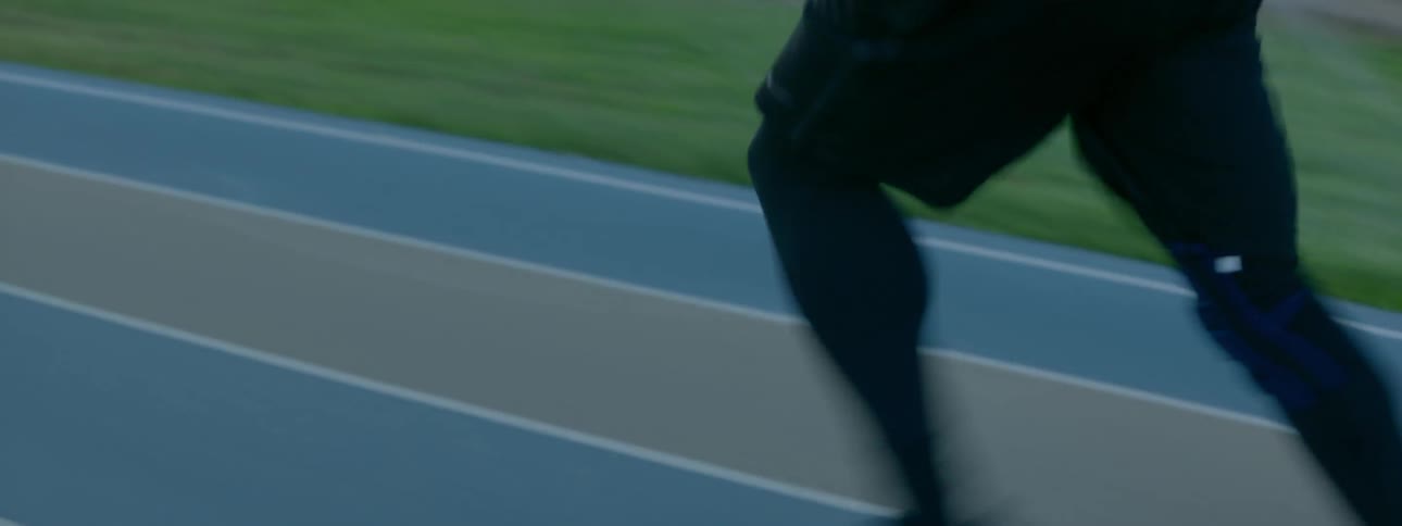 A man runs on a racetrack at sunset