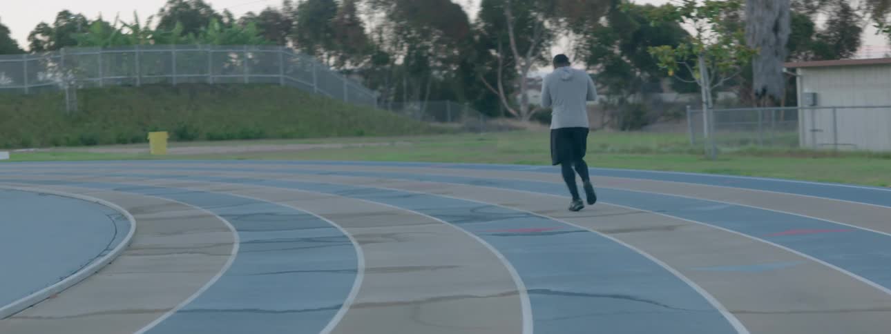 Man jogging around a racetrack on a cloudy day