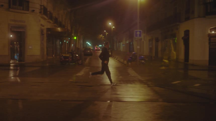 A man is running down the city street at night