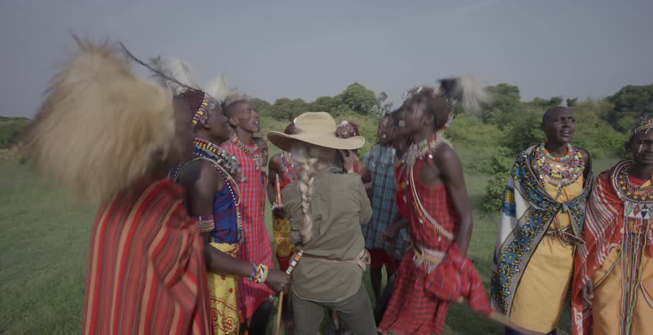 Maasai dance and chant in a circle around a photographer