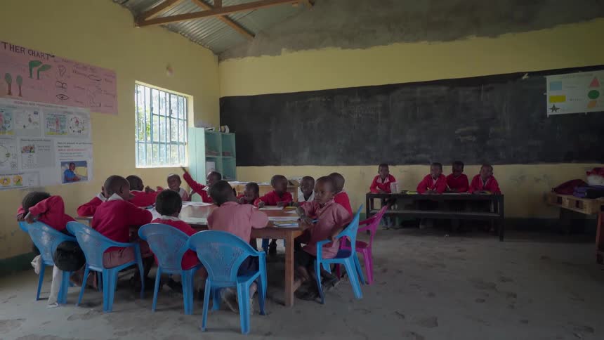 Students gather around a table in a classroom