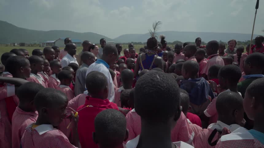 Students stand around a person in native dress and listen
