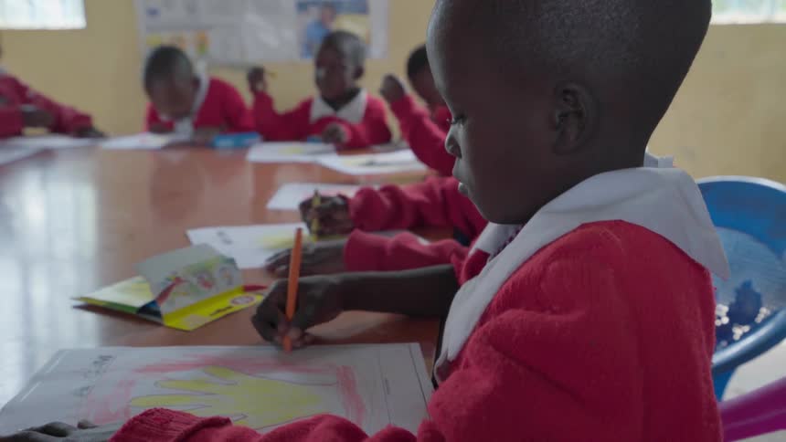 Children color at a table in class