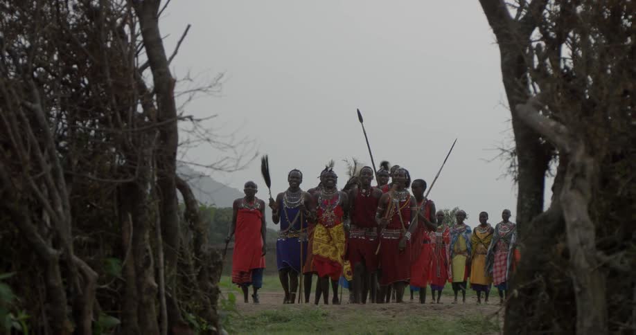 Maasai in costumes dance and sing outside during the day