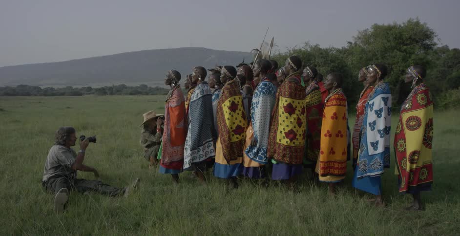 Men film maasai women doing a tribal dance in a field