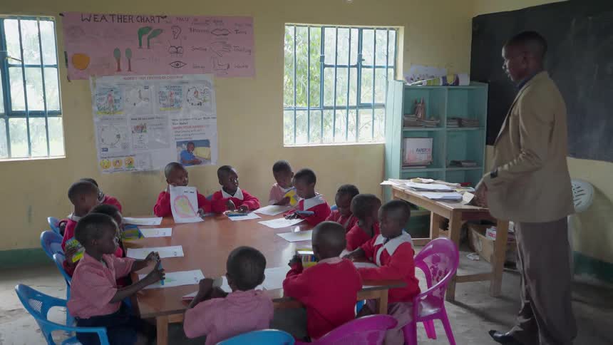 A teacher is talking with children at a table