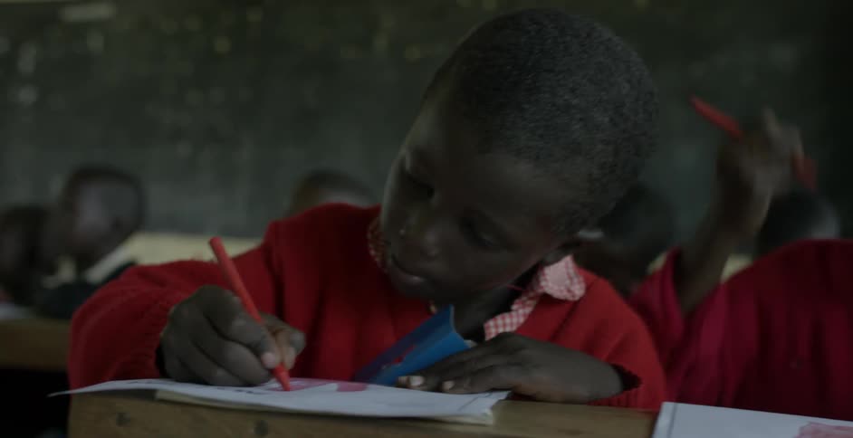 Students crowded together write and draw on paper