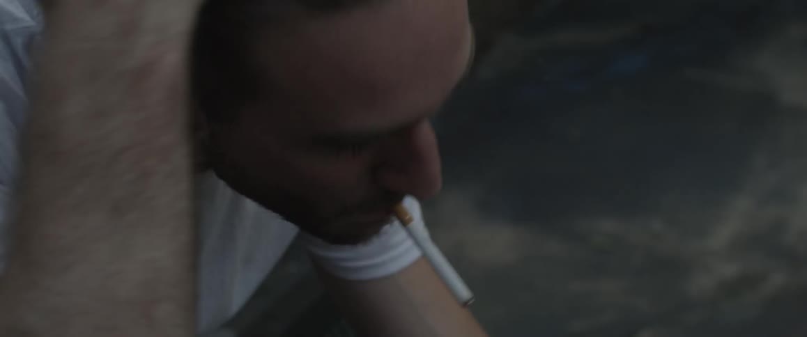 A man lights up and smokes a cigarette outside
