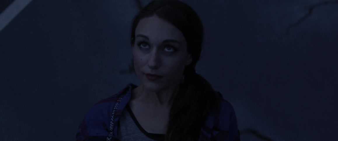 A woman looks around while a dark background moves behind her