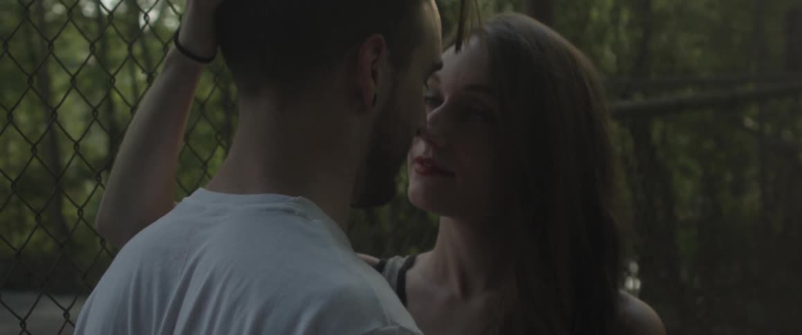 A man and woman touch each other affectionately outside
