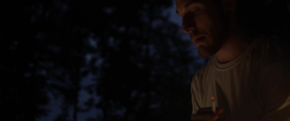 A person smokes outside near a light