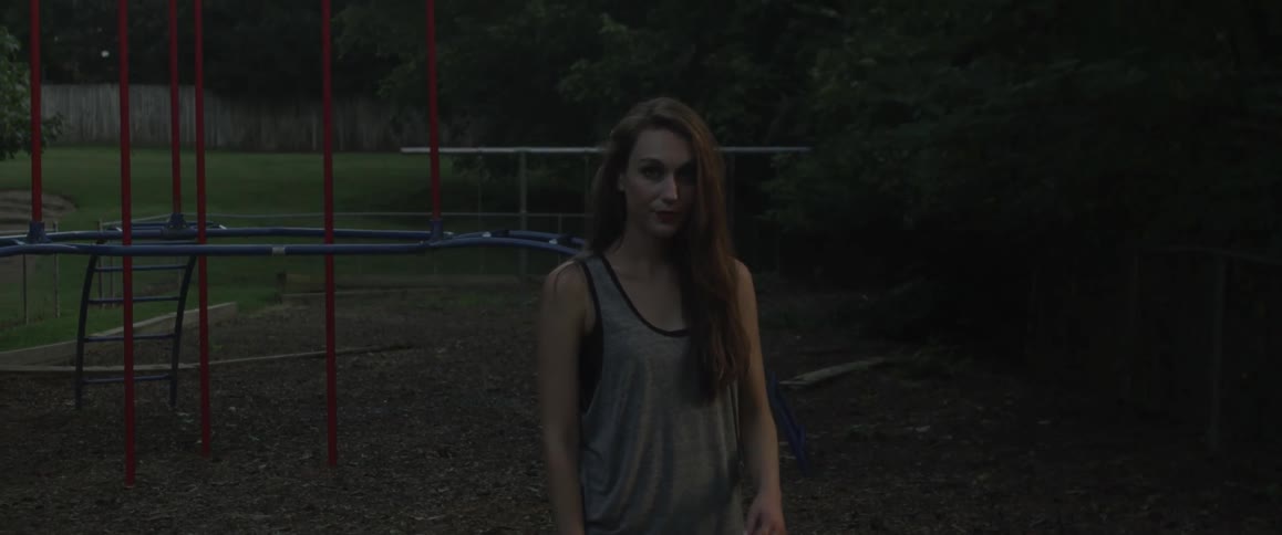 A woman brushes back her hair as she stands in a playground