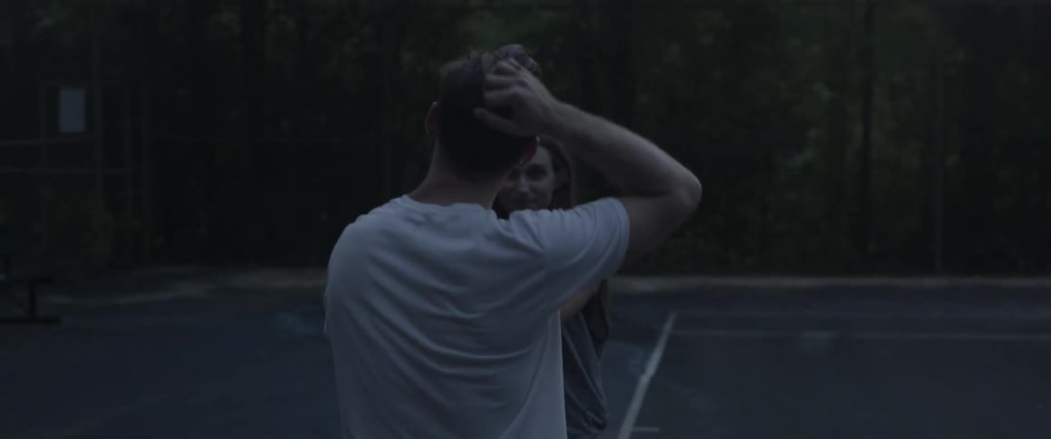 Young couple walking playfully while holding hands outdoors at dusk