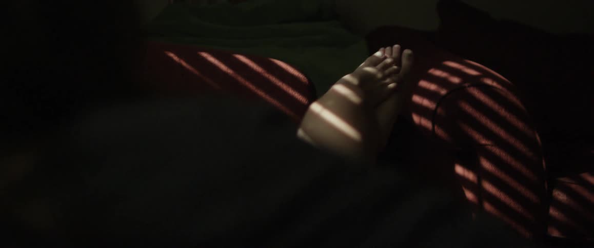 A person rubs their feet together on a couch