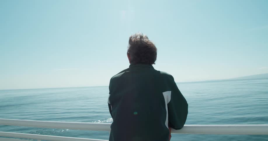 A man leans against the railing on a boat