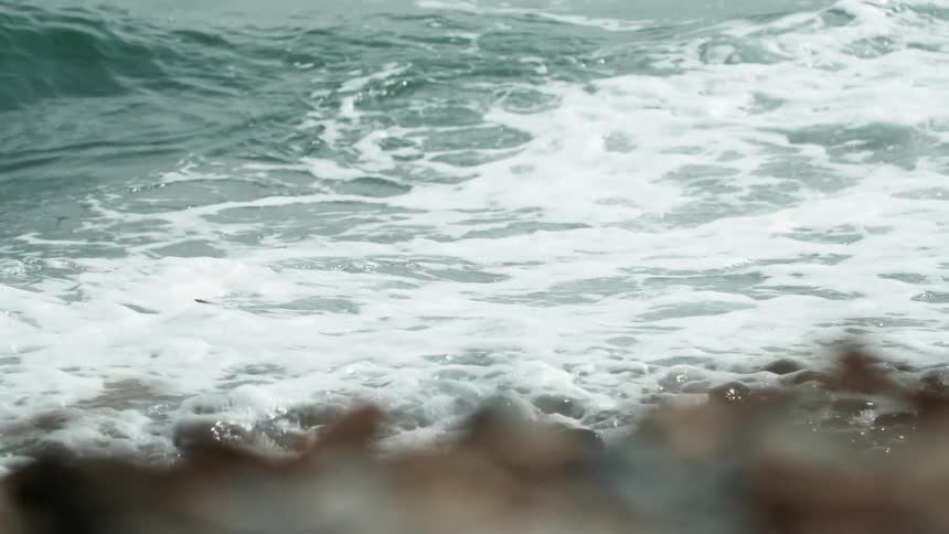 The waves crash against the pebble filled shore