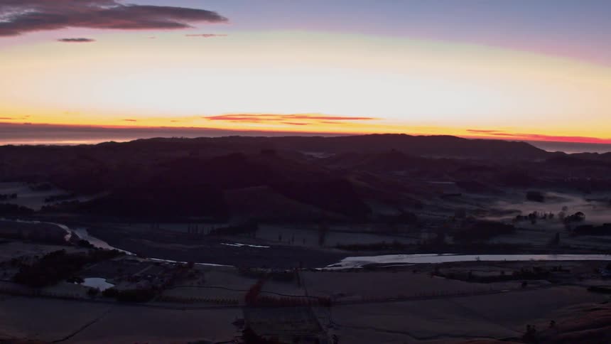 The sun sets behind a valley